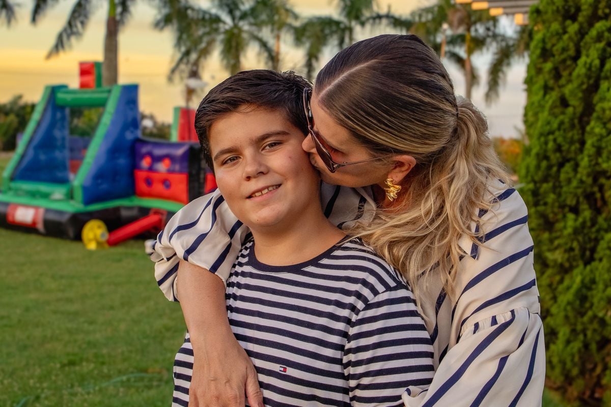 Mãe abraçando e beijando o filho num encontro de família ao ar livre, no Paraná