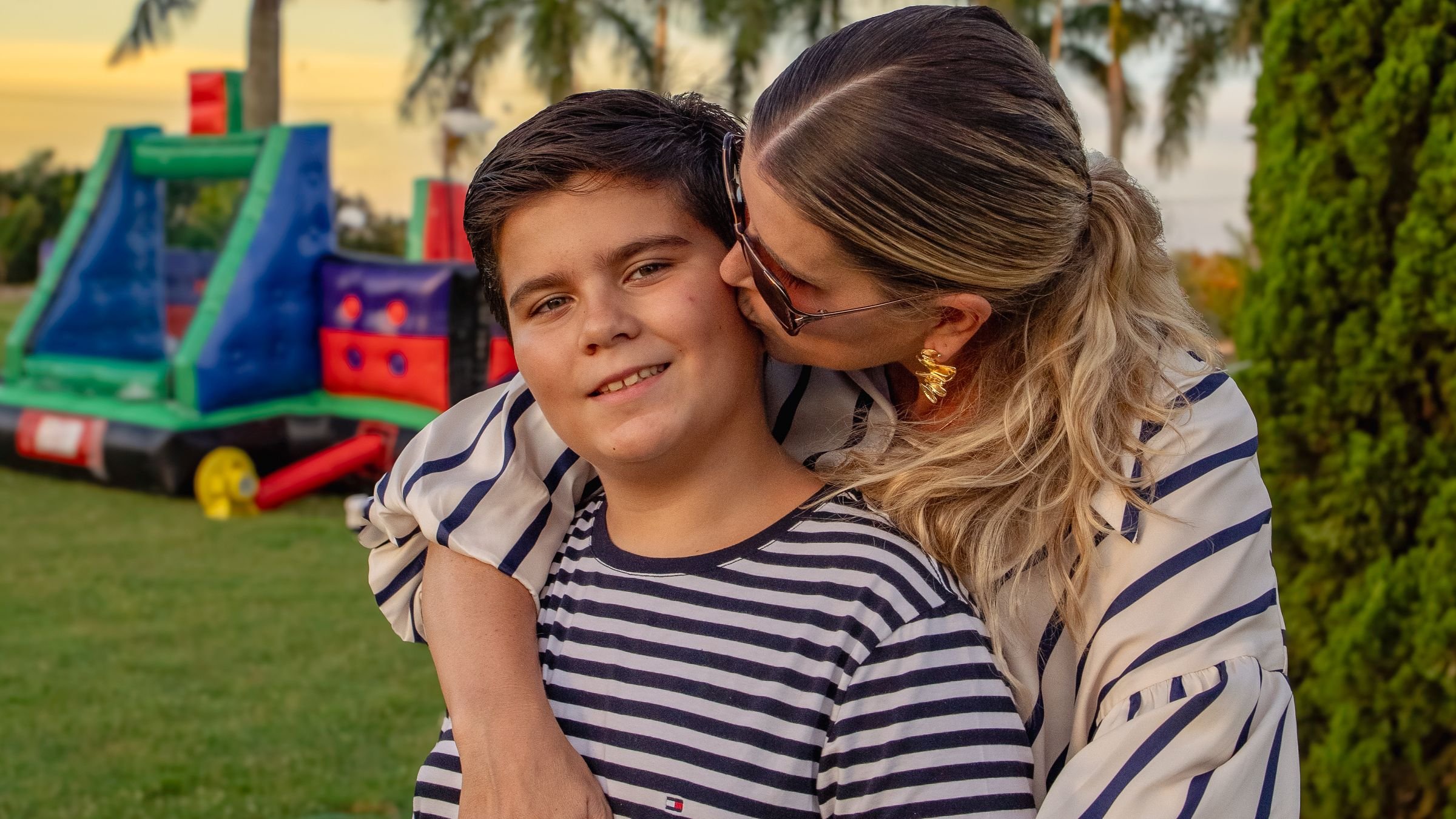 Mãe abraçando e beijando o filho num encontro de família ao ar livre, no Paraná