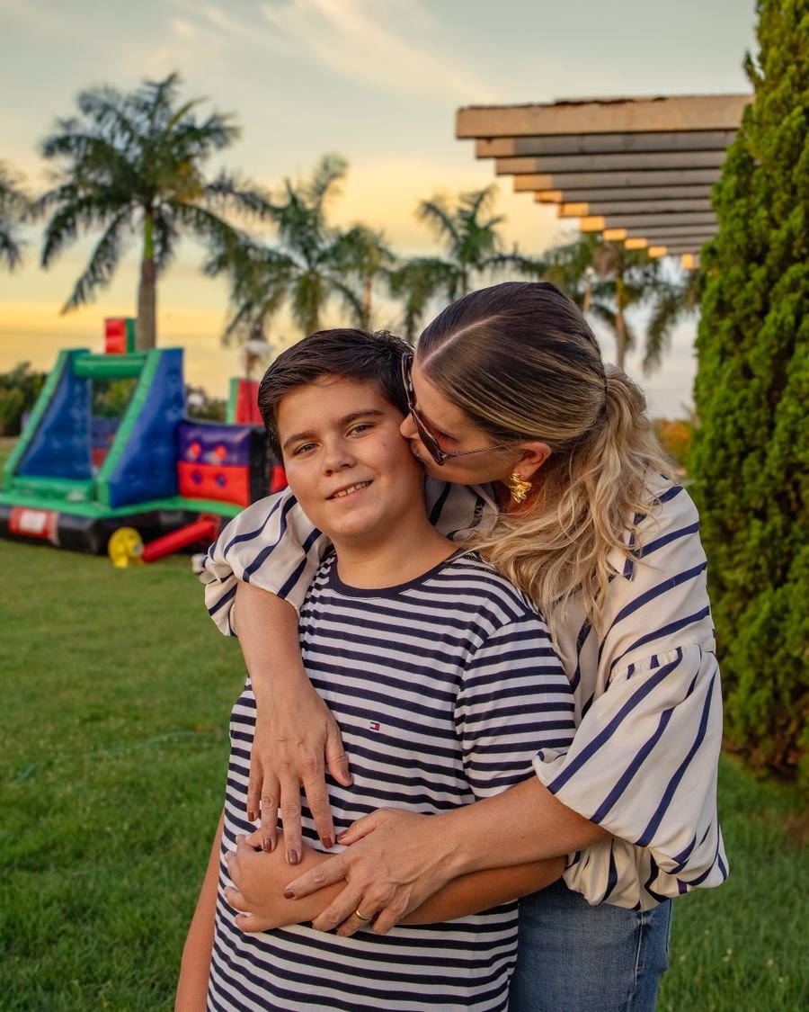 Mãe abraçando e beijando o filho ao ar livre