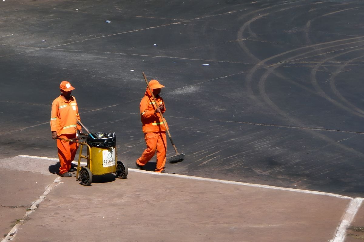 Dois garis de uniforme laranja trabalhando numa rua de Brasília