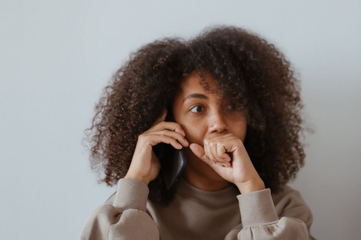 Mulher ao telefone, preocupada, com documentos espalhados ao redor