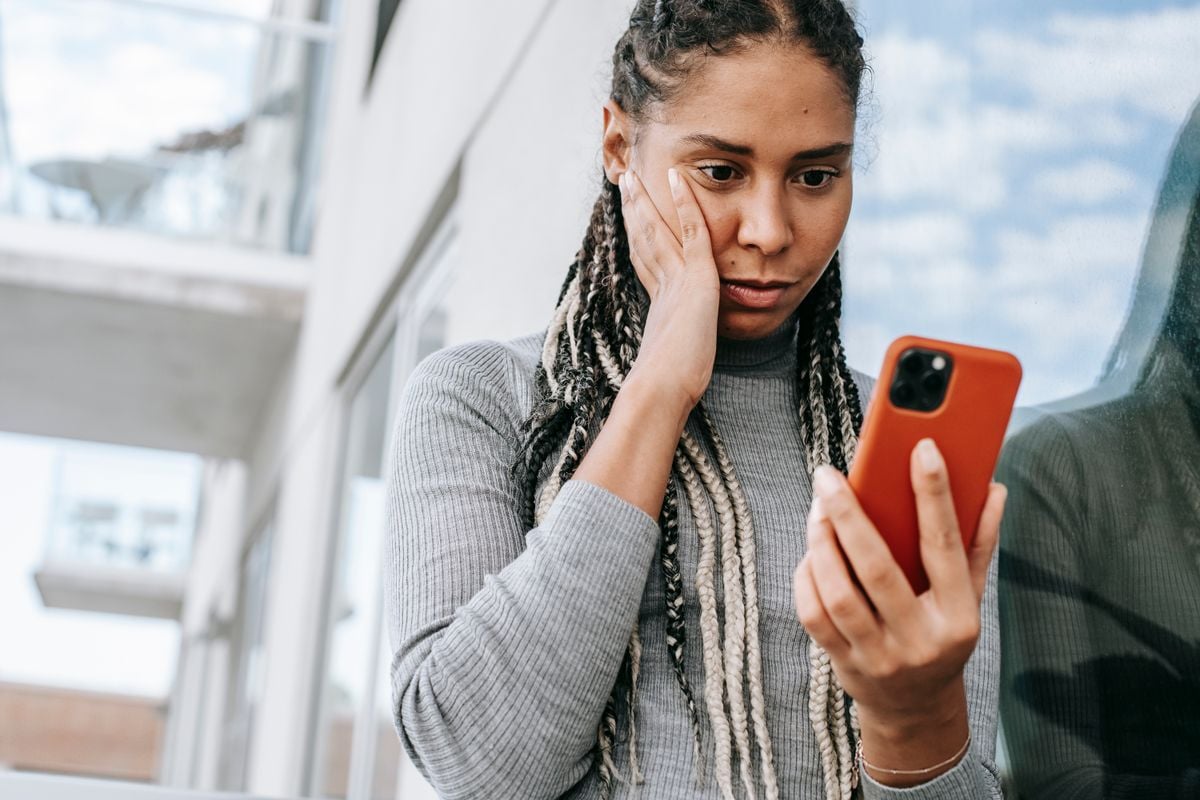 Mulher preocupada olhando o celular na rua