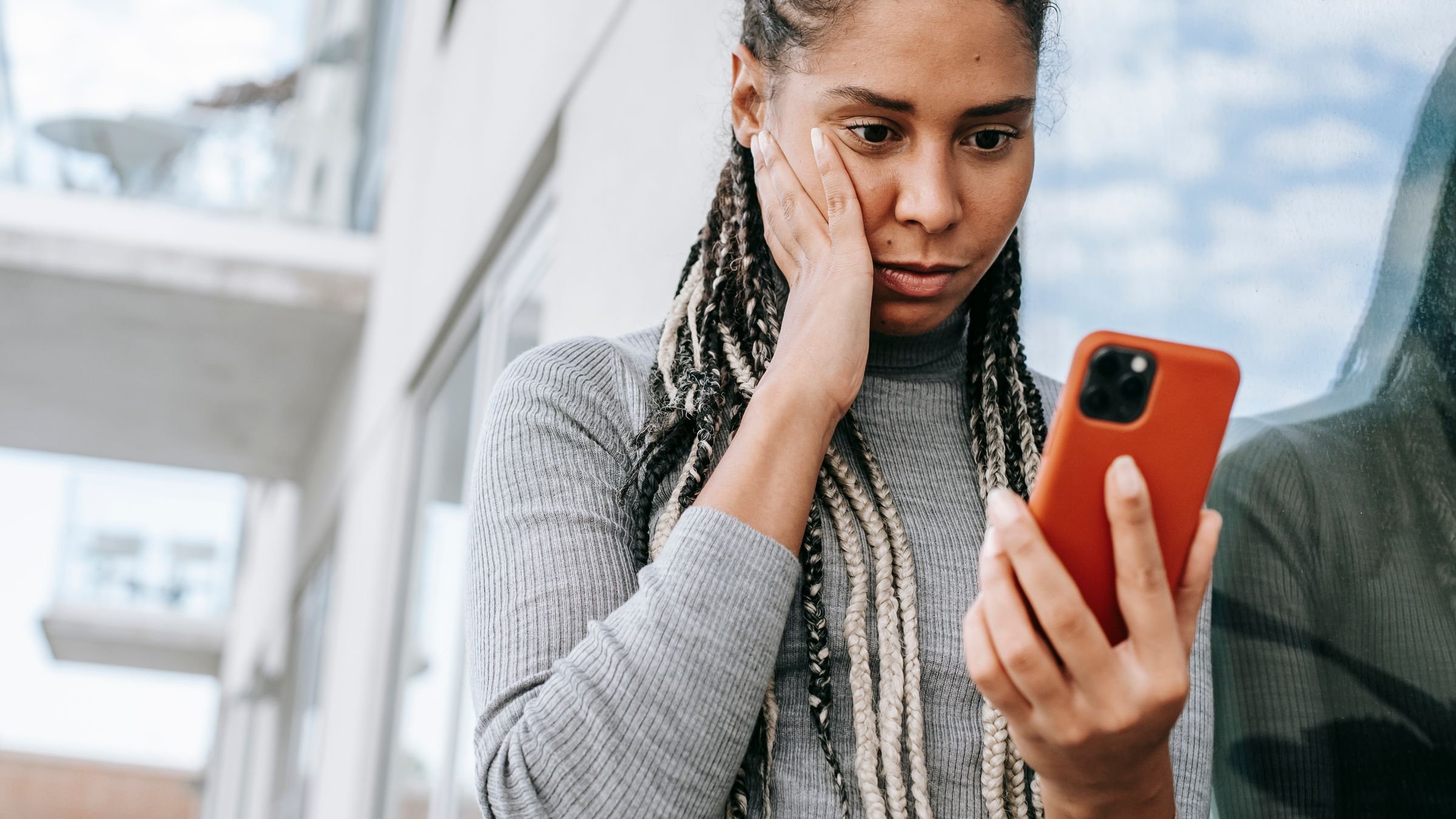 Mulher preocupada olhando o celular na rua