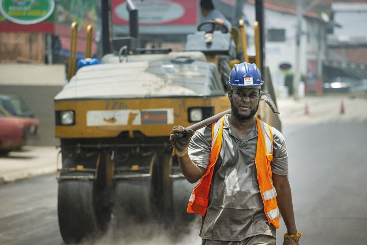 Trabalhador da construção civil com capacete e colete, numa rua de Cotia
