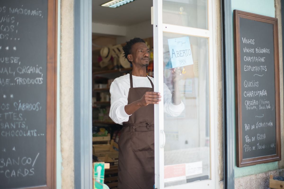 Comerciante abrindo a porta da própria mercearia pela manhã